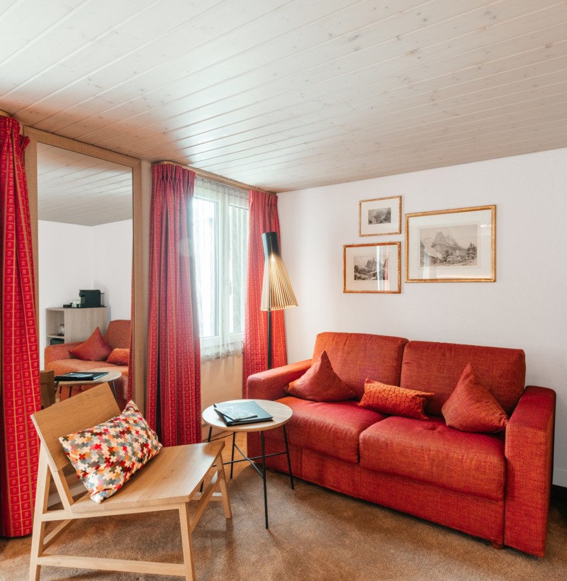 Cozy living room with red sofa and wooden accents under a white beamed ceiling, evoking warmth and relaxation, ideal for interior design themes.