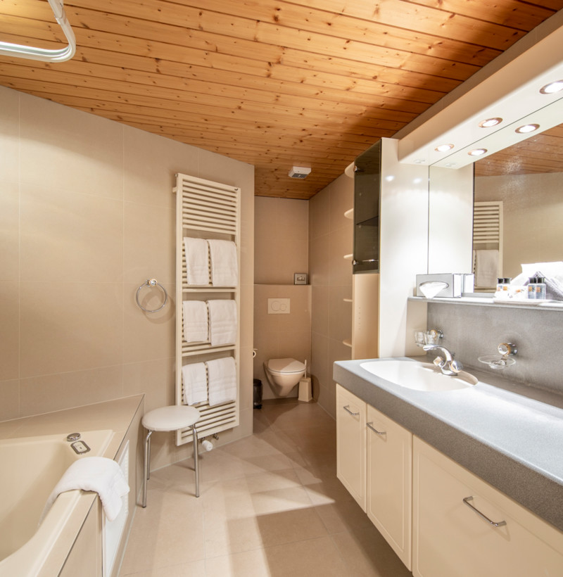 Warm, cozy bathroom with wooden ceiling and beige tiles, offering a serene, spa-like atmosphere for relaxation.