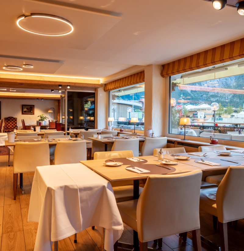 Elegant dining room with warm wooden floors and cream chairs, exuding a cozy, welcoming atmosphere ideal for culinary experiences.