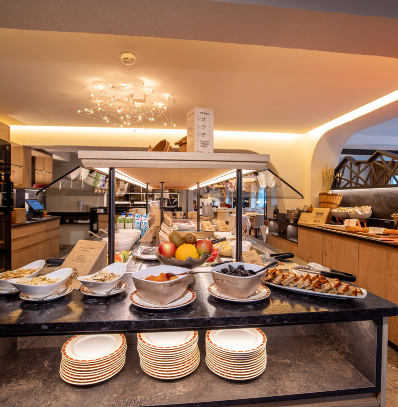 Warmly-lit buffet area with wooden accents and a variety of ready-to-serve dishes, inviting a cozy and appetizing experience for dining enthusiasts.
