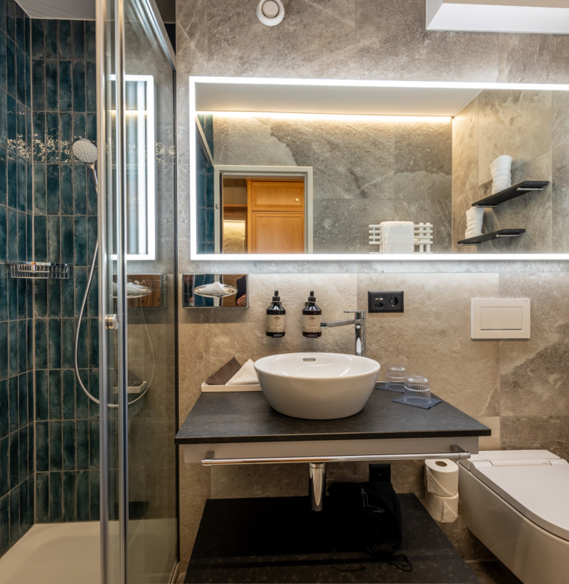 Elegant bathroom with deep blue tiles and sleek grey walls, presenting a serene and upscale atmosphere for design aficionados.