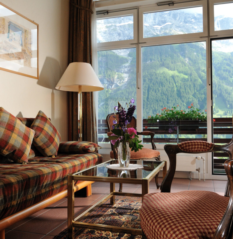 Cozy living room with plaid sofas and a striking mountain view, presenting a warm, inviting ambiance for travel and hospitality.