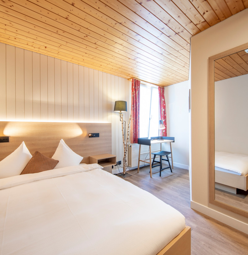 Cozy hotel room featuring warm wooden accents and crisp white bedding, evoking a serene, welcoming atmosphere for travelers.
