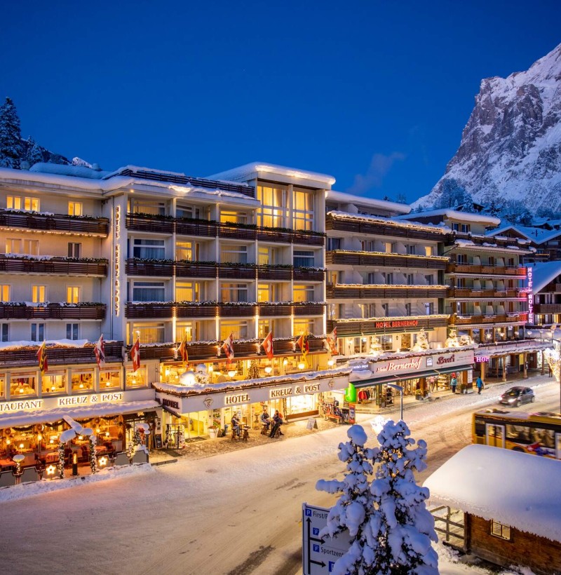 Twilight over a snow-covered alpine hotel glowing warmly, setting a serene yet vibrant scene for winter tourism.