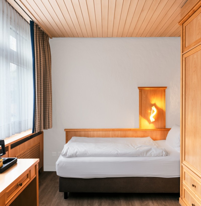 Cozy hotel room with warm wooden furniture and soft natural lighting, creating a peaceful retreat for travelers.