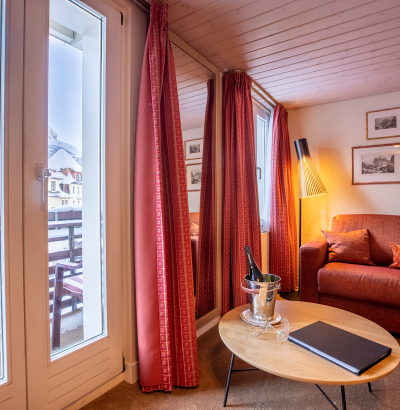 Cozy, warm-toned living room with a view of snow-covered mountains, ideal for travel and hospitality settings.