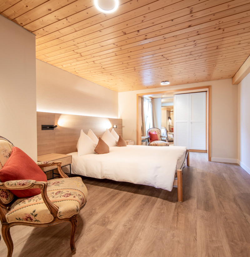 Cozy hotel room with warm wooden ceilings and elegant furnishings, inviting a sense of relaxation and comfort for travelers.