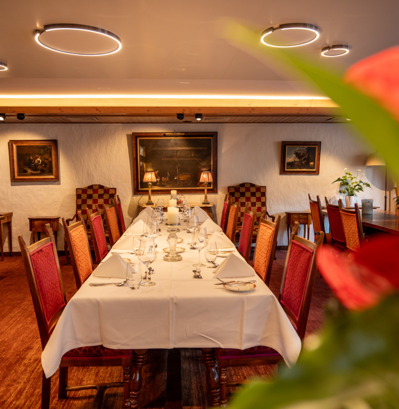 Elegant dining room with warm wood tones and white linens, inviting a cozy, upscale dining experience for culinary enthusiasts.