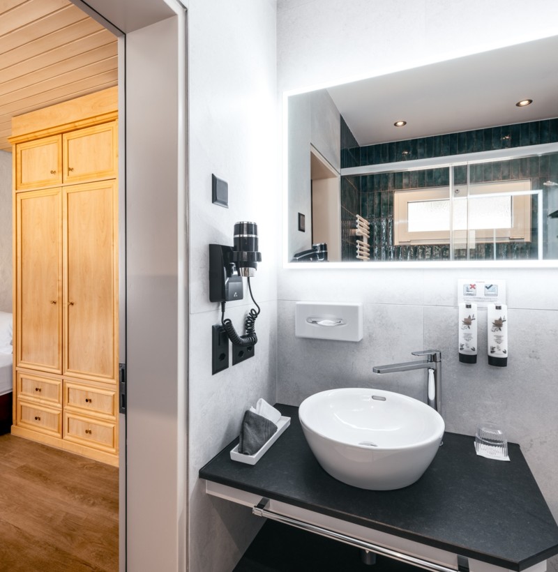 Sleek hotel room seamlessly integrates sleep and wash areas, with warm wooden tones offering a homely, inviting atmosphere.