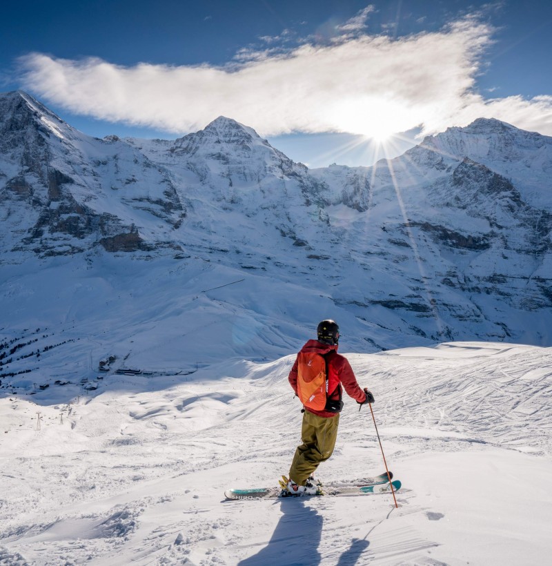 Skier dressed in a red jacket against a snowy mountain backdrop, capturing the thrill of winter sports.