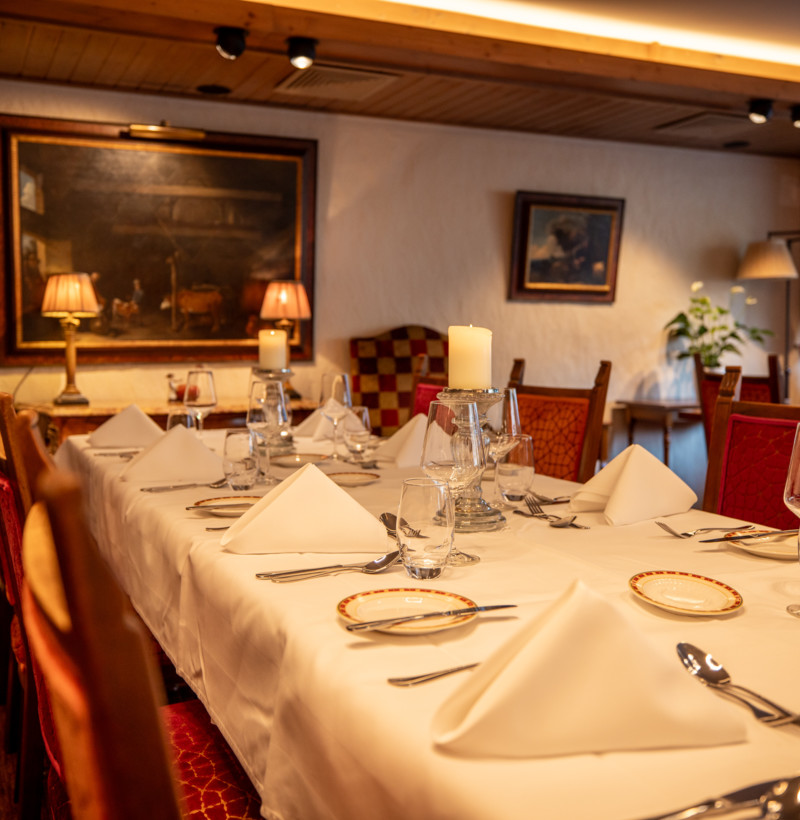 Elegant dining setup with red and gold chairs, white tablecloths, and soft lighting, creating a warm, inviting atmosphere for fine dining experiences.