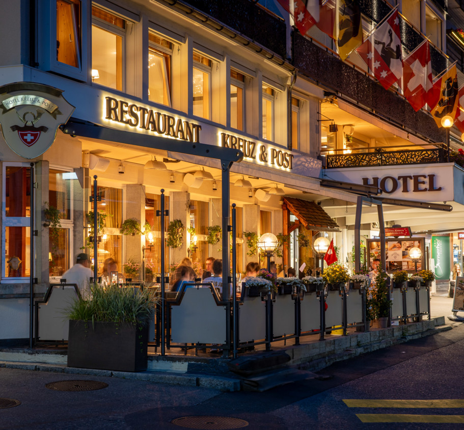 Twilight at a bustling street-side restaurant, highlighted by warm lighting and lively dining scenes, evokes a cozy, welcoming ambiance for tourists and food lovers.