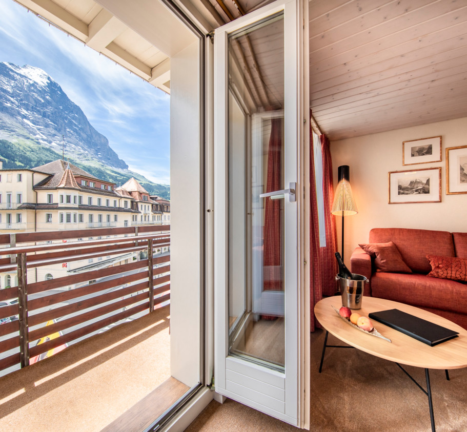 Cozy alpine retreat with red sofa and wooden interiors, offering a serene escape with stunning mountain views ideal for travel and leisure.