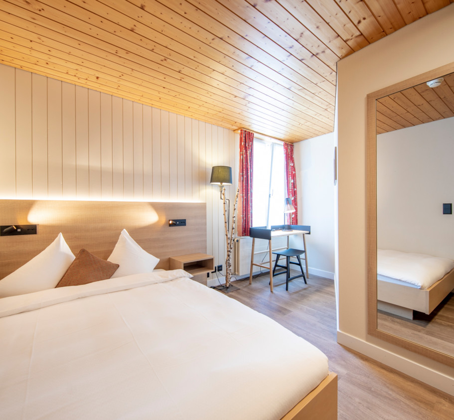 Cozy hotel room with a warm wood ceiling and crisp white linens, creating a tranquil, welcoming space for travelers.