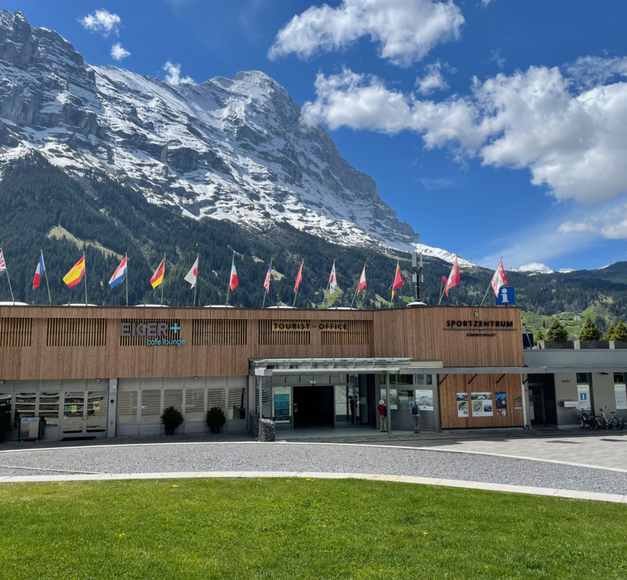 Alpine tourist center with striking wooden architecture under majestic snow-capped mountains, exuding a vibrant yet serene ambiance for travelers.