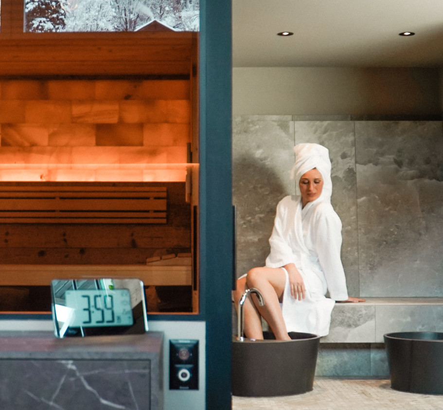 Soothing spa setting with wooden sauna and modern bathtub, featuring a serene woman in a white robe and towel, ideal for wellness retreats.