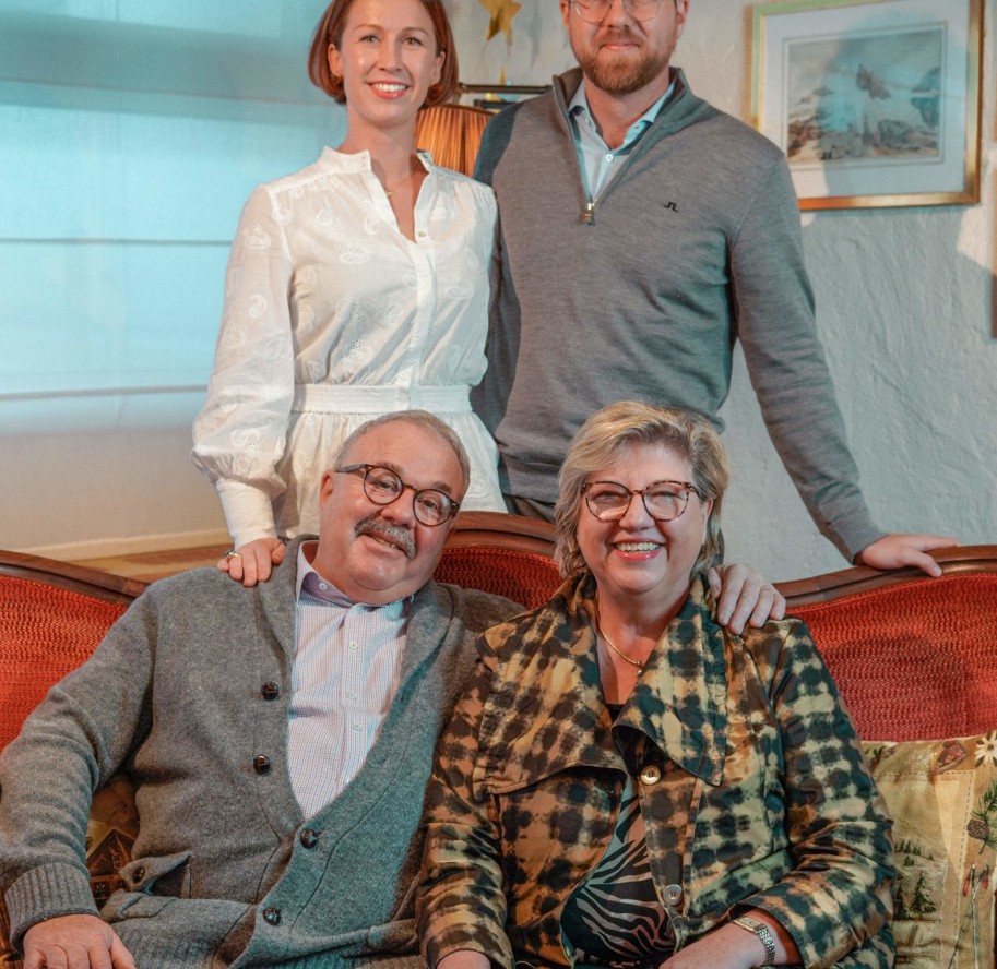 Family of four smiling warmly in a cozy, traditional living room, evoking a sense of togetherness and contentment, ideal for family-oriented services.